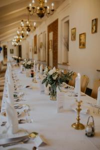 a long table with white linen and flowers on it at Hotel Zamek Pułtusk Dom Polonii in Pułtusk