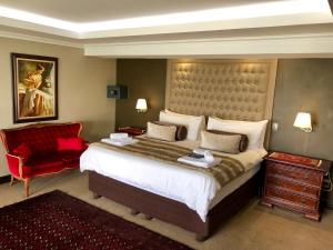 a bedroom with a large bed and a red chair at Kosmos Lodge in Hartbeespoort