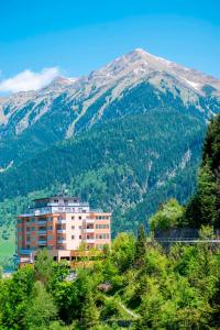 a large building in front of a mountain at Panorama SPA Aparthotel Schillerhof by AlpenTravel in Bad Gastein