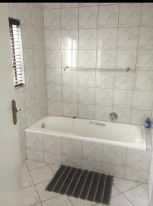 eine weiße Badewanne im Bad mit einem Teppich in der Unterkunft Kosmos Lodge in Hartbeespoort