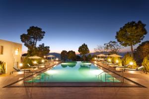 a swimming pool with lounge chairs and lights at night at Suryavilas Luxury Resort & Spa in Kasauli