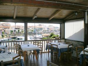 a restaurant with tables and chairs with a view of a harbor at Lina Hotel in Stintino