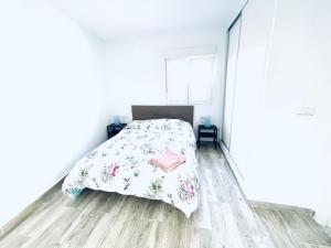 a white bedroom with a bed and a wooden floor at Super Exclusive Bungalow in Benalmádena