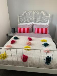 a white bed with pink and yellow pillows on it at My Perfect Place Rooms & Apartments -Some rooms with Hot Tub- Free Parking in Blackpool