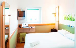 a bedroom with a bed and a laptop on a desk at ibis budget London Hounslow in Hounslow