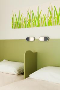 a bedroom with two beds and a plant on the wall at ibis budget London Hounslow in Hounslow