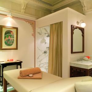 a room with a bed, a mirror, and a dresser at Taj Lake Palace Udaipur in Udaipur