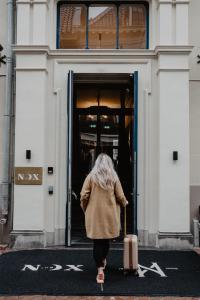 a woman walking out of a building with a suitcase at The Nox Hotel in Utrecht