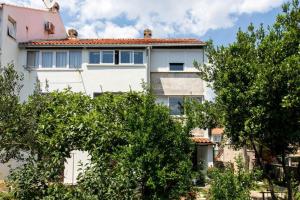 una casa bianca con degli alberi di fronte di Apartment Tetepave a Dubrovnik