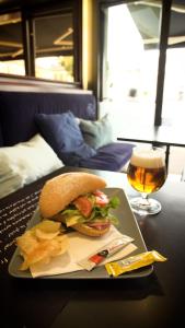 ein Sandwich auf einem Teller neben einem Laptop und ein Glas Bier in der Unterkunft Hotel Le Derby in Quimper