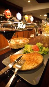 einen Teller mit Essen auf der Theke mit einem Glas Wein in der Unterkunft Hotel Le Derby in Quimper