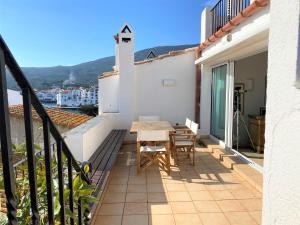 einen Balkon mit einem Tisch und Stühlen auf einem Gebäude in der Unterkunft PALAU - Gran casa de pueblo con fantásticas vistas al mar in Cadaqués