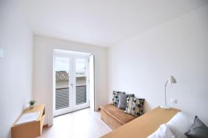 a bedroom with a bed and a door leading to a balcony at Casa da Baía - Guest House in Horta