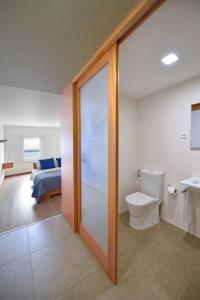 a bathroom with a toilet and a bedroom at Casa da Baía - Guest House in Horta