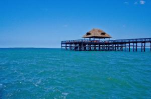 a pier in the ocean with a thatch roof at White Sands Hotel in Dar es Salaam
