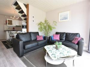 a living room with black leather couches and a table at Holiday Home in Bredene Terrace Fenced Garden in Bredene