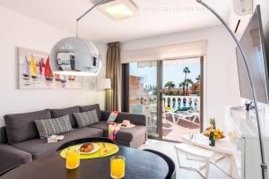 een woonkamer met een bank en een tafel bij Tenerife Royal Gardens - Viviendas Vacacionales in Playa de las Americas