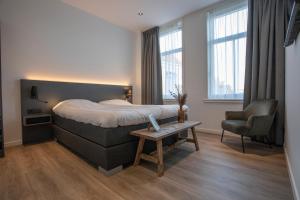 een slaapkamer met een bed, een stoel en een tafel bij Hotel Tholen in Tholen