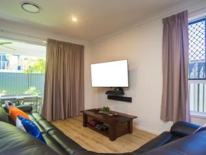 sala de estar con sofá y TV de pantalla plana en Broadwater Paradise en Gold Coast