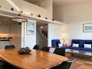 una sala da pranzo e un soggiorno con tavolo in legno e sedie blu di MATILLA - Apartamento con parquin a Cadaqués