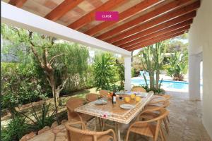 Una mesa y sillas en un patio con piscina. en Villa Marions, en Santanyí