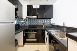 a kitchen with black counters and a sink at Spacious 1BR Botanica Towers, Dubai Marina in Dubai