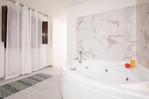 a white bathroom with a tub and marble walls at Unforgettable Split Level Jacuzzi Suite Navona - Top Collection in Rome +18 photos