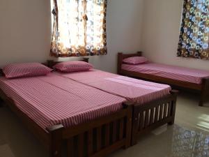 two beds in a room with pink sheets at Shantham Service Apartments, Kinathukadavu, Coimbatore in Coimbatore