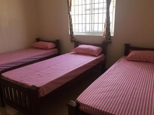 três camas num quarto com riscas vermelhas e brancas em Shantham Service Apartments, Kinathukadavu, Coimbatore em Coimbatore
