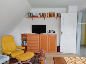 ein Wohnzimmer mit einem gelben Stuhl und einem TV in der Unterkunft Ferienwohnung Gül Waanang in Nebel