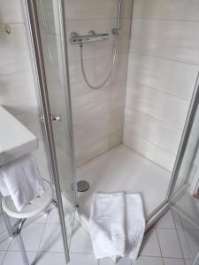 eine Dusche mit einer Glastür und einem Stuhl im Bad in der Unterkunft Alter Landkrug in Nortorf