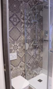 una doccia con porta in vetro accanto a servizi igienici di Le coin 45 a Colmar