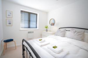 a white bedroom with a large white bed with two towels at Stylish Apartment with Private Parking in Cardiff