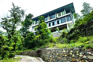 a building on top of a hill with a stone wall at Haut Monde Hill Stream Resort and Spa in Dehradun