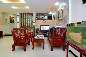 sala de estar con sillas, mesa y TV en Cosy House Homestay, en Hoi An