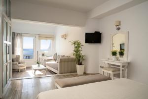 Sala de estar blanca con sofá y espejo en Delfini Villas en Oia