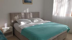Un dormitorio con una cama con sábanas azules y blancas y una ventana. en Apartman Villa Pećine, en Rijeka