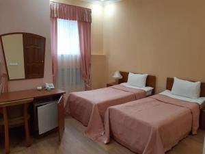 Zimmer mit 2 Betten, einem Schreibtisch und einem Spiegel in der Unterkunft Guest House Lux in Kislowodsk