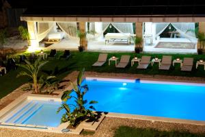 einen Pool in einem Garten mit Stühlen und einer Terrasse in der Unterkunft Relais Villa Lucia in Carovigno