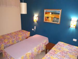 2 camas en una habitación con paredes azules en Residencial Villafranca, en Boicucanga