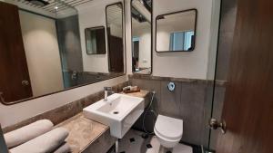 a bathroom with a sink and a toilet and mirrors at Polo Floatel Kolkata in Kolkata