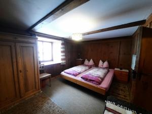 a bedroom with a bed with pink pillows on it at Bio Yak Hof Heinz in Sufers