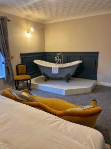 a bathroom with a bath tub and a chair at The Leagate Inn in Coningsby