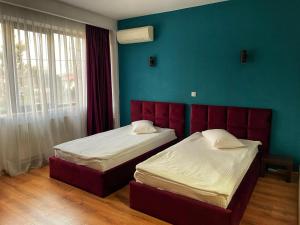 - une chambre avec 2 lits et un mur bleu dans l'établissement Hotel Best, à Ploieşti