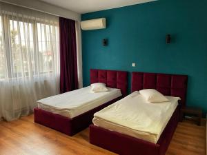 1 dormitorio con 2 camas y pared azul en Hotel Best, en Ploieşti