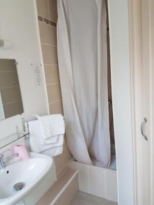 a bathroom with a shower curtain and a sink at Ardenn'Hotel in Reims