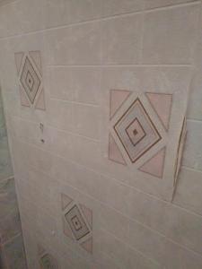 una pared de azulejos blancos con diamantes rosas. en Ardenn'Hotel, en Reims