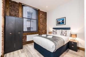 1 dormitorio con 1 cama grande y pared de ladrillo en 27 Stanley Street Aparthotel by UStay, en Liverpool