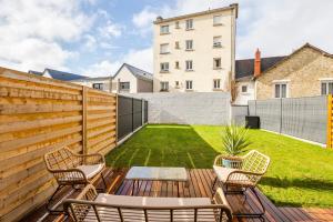 a backyard with a wooden fence and chairs and a lawn at Maison Twin Sister in Rennes