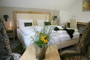 ein Schlafzimmer mit einem Bett und einem Tisch mit einer Blume in der Unterkunft Gästehaus an der Sempt - Wohlfühlen auf dem Lande in Erding